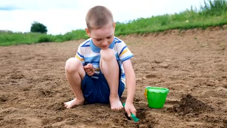 Little-boy-is-playing-digging-a-pit-with-a-shovel.-Kid-playing-on-the-beach