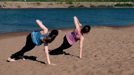 Two-woman-doing-the-exercises-sports-on-the-banks-of-the-river-in-the-city.-Exercises-for-hands-in-the-plank.