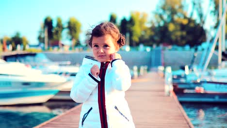 Little-baby-girl-dreams-about-something-on-the-pier-for-boats-and-yachts