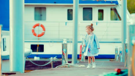 Girl-child-is-walking-along-the-pier-for-yachts-and-boats