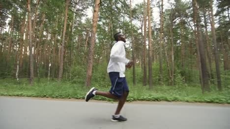 Hombre-negro-cansado-de-correr-a-lo-largo-de-camino-forestal