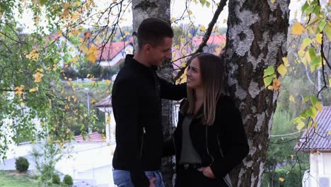 A-young-couple-sits-on-a-white-bedspread-in-autumn-park