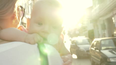 Mum-with-baby-walking-outside-against-bright-sun-flare