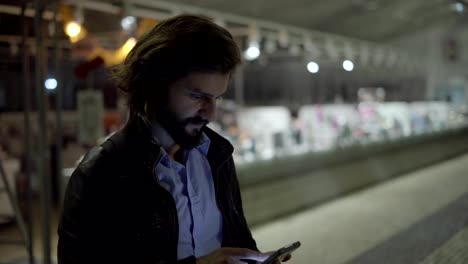 Handsome-man-using-smartphone-near-showcase-in-night-city