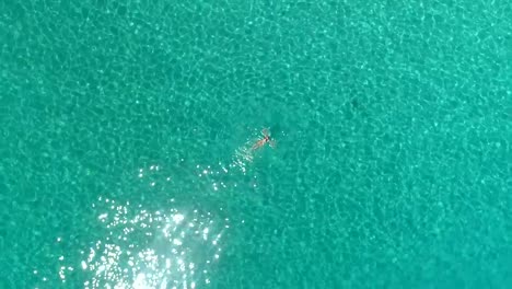 Aerial-view-of-a-woman-swimming-in-the-sea-of-Atokos-island,-Greece