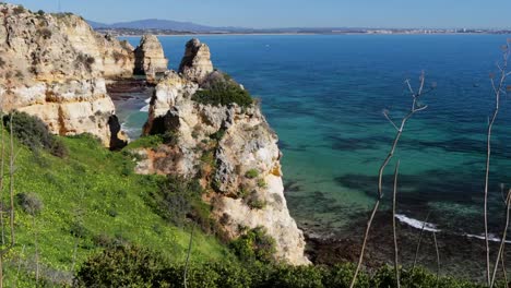 Ponta-da-Piedade,-berühmter-Ort-im-Süden-Portugals,-Lagos-Stadt,-Die-felsige-Küste,-die-Wellen-des-Atlantischen-Ozeans,-scharfe-Felsen,-azurblaues-Wasser,-gelbe-Blumen,-Bogen,-niemand,-wilder-Strand