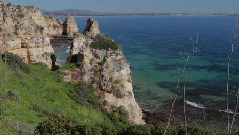 Ponta-da-Piedade,-lugar-famoso-en-el-sur-de-Portugal,-la-ciudad-de-lagos,-la-costa-rocosa,-olas-de-océano-Atlántico,-rocas-afiladas,-agua-azul,-flores-amarillas,-arco,-nadie,-playa-salvaje