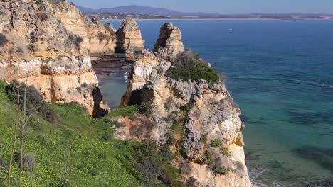 Ponta-da-Piedade,-berühmter-Ort-im-Süden-Portugals,-Lagos-Stadt,-Die-felsige-Küste,-die-Wellen-des-Atlantischen-Ozeans,-scharfe-Felsen,-azurblaues-Wasser,-gelbe-Blumen,-Bogen,-niemand,-wilder-Strand