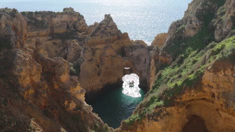 Ponta-da-Piedade,-lugar-famoso-en-el-sur-de-Portugal,-la-ciudad-de-lagos,-la-costa-rocosa,-olas-de-océano-Atlántico,-rocas-afiladas,-agua-azul,-flores-amarillas,-arco,-nadie,-playa-salvaje