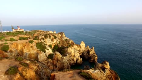 Ponta-da-Piedade-lighthouse-on-cliff-near-ocean-at-sunset,-Lagos,-aerial-view