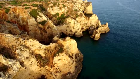 Faro-de-Ponta-da-Piedade-en-acantilado-junto-al-mar-en-vista-aérea-de-la-puesta-del-sol,-Lagos,