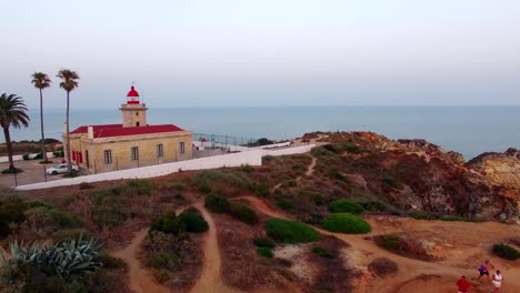 Ponta-da-Piedade-lighthouse-on-cliff-near-ocean-at-sunset,-Lagos,-aerial-view