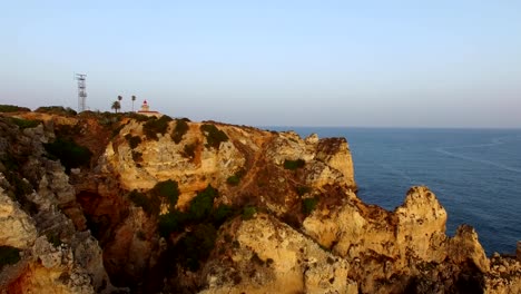 Ponta-da-Piedade-lighthouse-on-cliff-near-ocean-at-sunset,-Lagos,-aerial-view