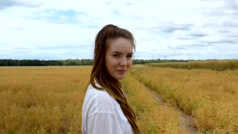 Joven-mujer-caminando-por-un-campo-de-hierba-dorada