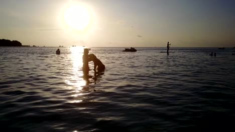 v04132-vuelo-drone-vista-aérea-de-Maldivas-playa-2-personas-pareja-hombre-mujer-amor-romántico-puesta-de-sol-salida-del-sol-en-la-isla-de-paraíso-tropical-soleado-con-cielo-azul-aqua-agua-mar-4k