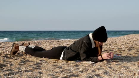 Chica-está-descansando-acostado-en-la-orilla-del-mar-Mediterráneo-en-un-día-frío-de-otoño