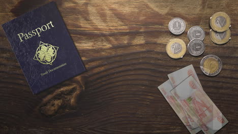 Wood-table-with-travel-passport-and-metal-coin-and-paper-money