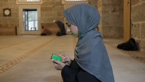 Faithful-girl-using-green-screen-in-mosque