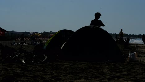 Silhouette-young-man-picking-up-tent