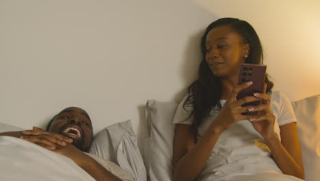 Couple-At-Home-At-Night-Lying-In-Bed-With-Woman-Looking-At-Mobile-Phone-4