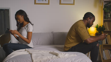 Couple-With-Relationship-Problems-At-Home-At-Night-Both-Looking-At-Mobile-Phones-In-Bedroom-5