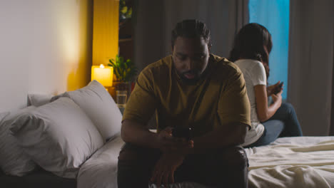 Couple-With-Relationship-Problems-At-Home-At-Night-Both-Looking-At-Mobile-Phones-In-Bedroom-10