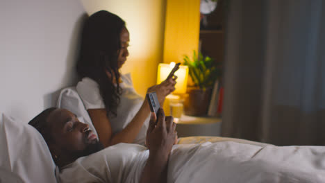 Couple-With-Relationship-Problems-At-Home-At-Night-Both-Looking-At-Mobile-Phones-In-Bedroom-11