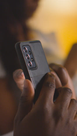 Vertical-Video-Close-Up-Of-Couple-At-Home-At-Night-Both-Looking-At-Their-Mobile-Phones-In-Bed