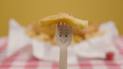 Person-Eating-Traditional-British-Takeaway-Meal-Of-Fish-And-Chips-Holding-Wooden-Fork-With-Smiling-Face