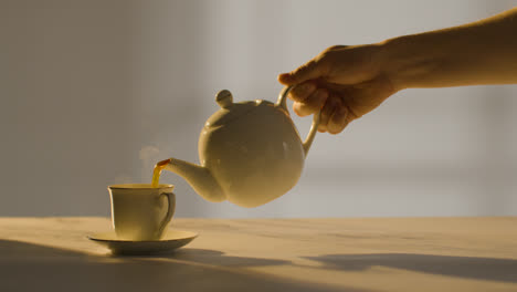 Studioaufnahme-Einer-Person,-Die-Mithilfe-Der-Teekanne-1-Eine-Traditionelle-Britische-Tasse-Tee-Zubereitet-Und-Einschenkt
