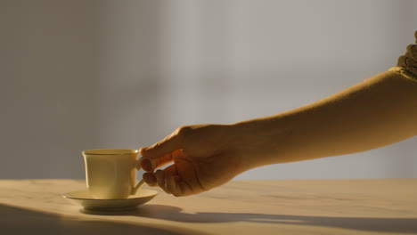 Studio-Shot-Of-Person-Picking-Up-And-Drinking-Traditional-Steaming-British-Cup-Of-Tea-With-Copy-Space