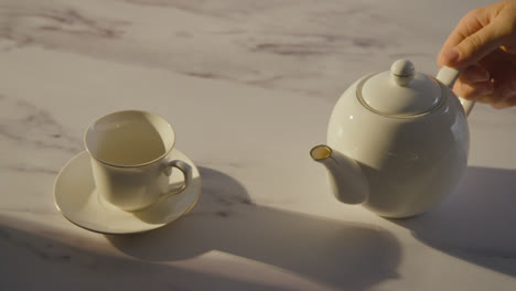 Studioaufnahme-Einer-Person,-Die-Eine-Traditionelle-Britische-Tasse-Tee-Mit-Einer-Teekanne-Zubereitet