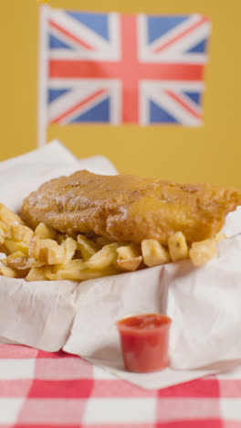 Vertical-Video-Of-Traditional-British-Takeaway-Meal-Of-Fish-And-Chips-With-Union-Jack-Flag