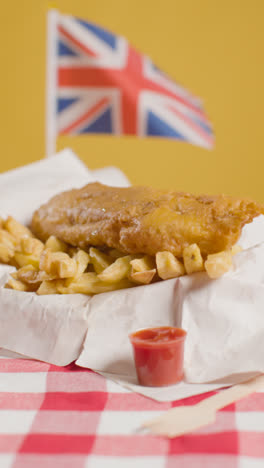 Vertical-Video-Of-Traditional-British-Takeaway-Meal-Of-Fish-And-Chips-With-Union-Jack-Flag-1