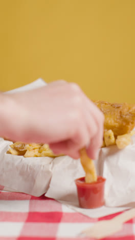 Vertikales-Video-Von-Menschen,-Die-Mit-Den-Fingern-Ein-Traditionelles-Britisches-Imbissgericht-Mit-Fish-And-Chips-Und-Ketchup-Essen