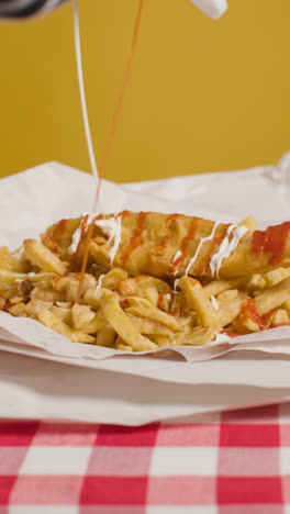 Vertical-Video-Studio-Shot-Of-Traditional-British-Takeaway-Meal-Of-Fish-And-Chips-Covered-With-Sauces