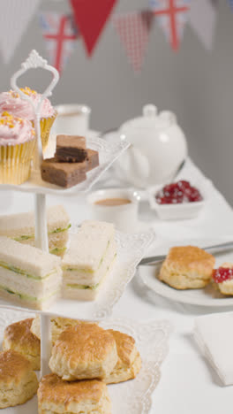 Vertical-Video-Studio-Shot-Of-Traditional-British-Afternoon-Tea-With-Sandwiches-Cake-Scones-Cream-And-Jam