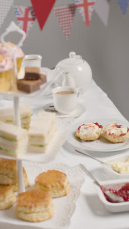 Vertical-Video-Studio-Shot-Of-Traditional-British-Afternoon-Tea-With-Sandwiches-Cake-Scones-Cream-And-Jam