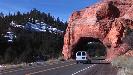 Medium-shot-of-a-car-passing-through-an-arch-over-the-highway-near-Zion-National-Park-in-Utah