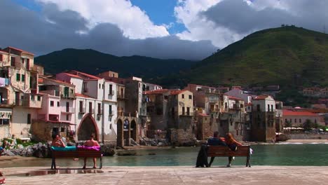 Paare-Sitzen-Auf-Einer-Bänke-Mit-Blick-Auf-Das-Meer-Und-Die-Häuser-In-Cefalu-Italien