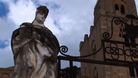A-cloud-time-lapse-moving-above-a-statue-of-a-woman-holding-a-book-in-Cefalu-Italy--