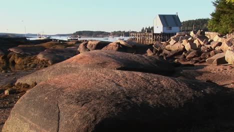 A-building-in-a-lobster-village-is-over-water-as-seen-from-a-rocky-shore-in-Stonington-Maine