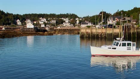 Un-Barco-Pasa-Por-Un-Muelle-Y-Un-Pueblo-De-Langostas-En-Stonington,-Maine