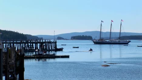 A-sailing-ship-is-at-anchor-near-a-wooden-pier-offshore-a-lobster-village-in-Stonington-Maine