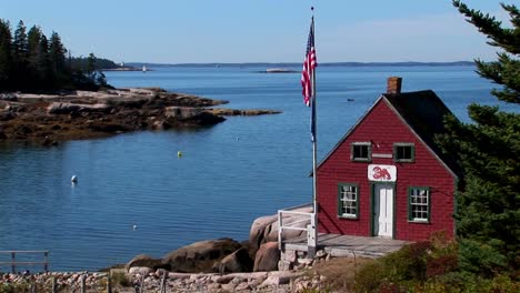 A-red-house-sits-on-the-edge-of-a-bay-at-a-lobster-village-in-Stonington-Maine