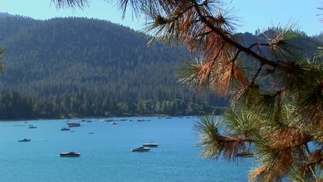 Boats-float-on-water-in-Lake-Tahoe-surrounded-by-treecovered-hills-in-the-Sierra-Nevada-mountains--