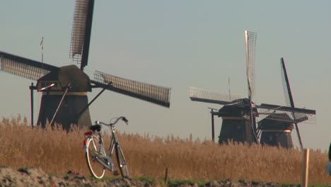 A-bicycle-is-parked-along-a-path-in-Holland-with-windmills-in-the-background