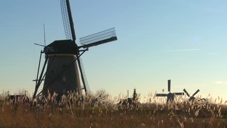 A-slow-pan-across-to-windmills-rising-from-the-grass-in-Holland