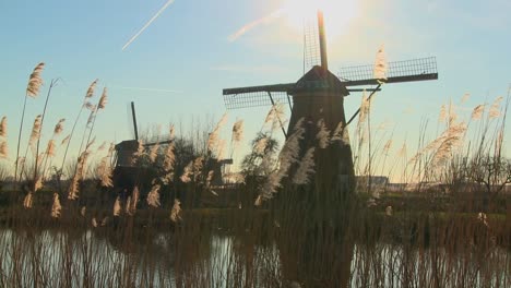 A-slow-tilt-up-to-windmills-standing-along-a-canal-in-Holland