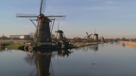 A-boat-moves-along-a-canal-in-Holland-with-windmills-nearby